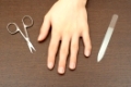 Scissors, glass nail file and a hand for manicure 